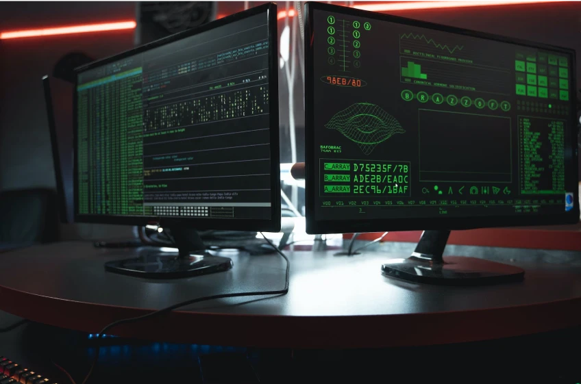 Two computer monitors in a dark room.