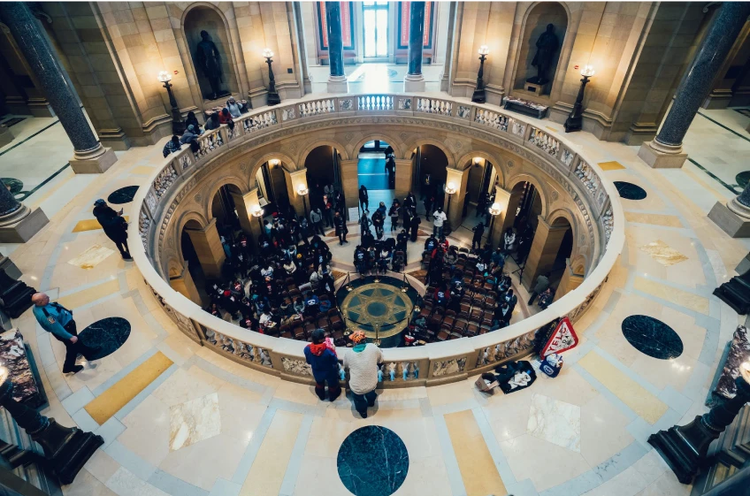 A group of people are standing on a circular floor in a building.