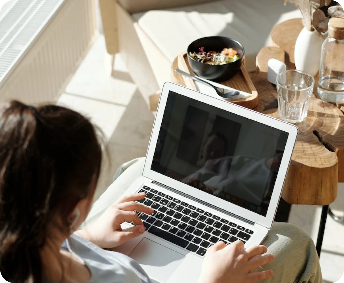A woman is using a laptop in front of a table.